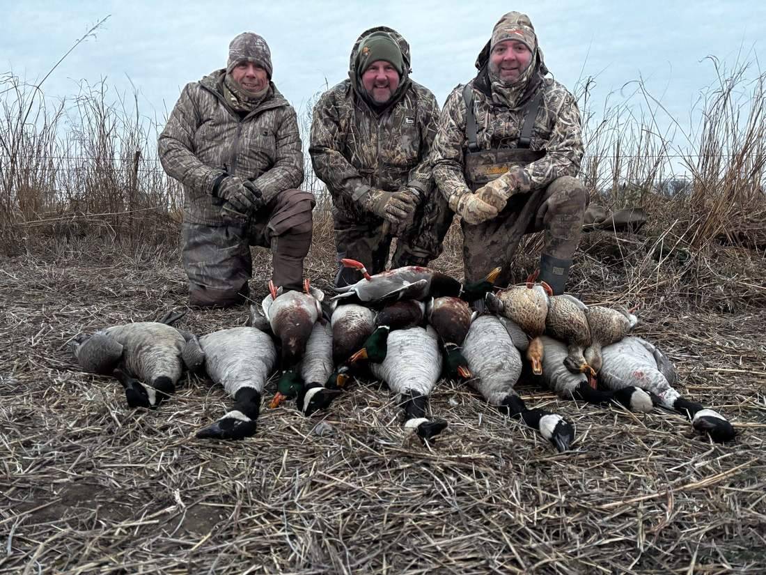 Three hunters kneeling behind a Kansas duck limit