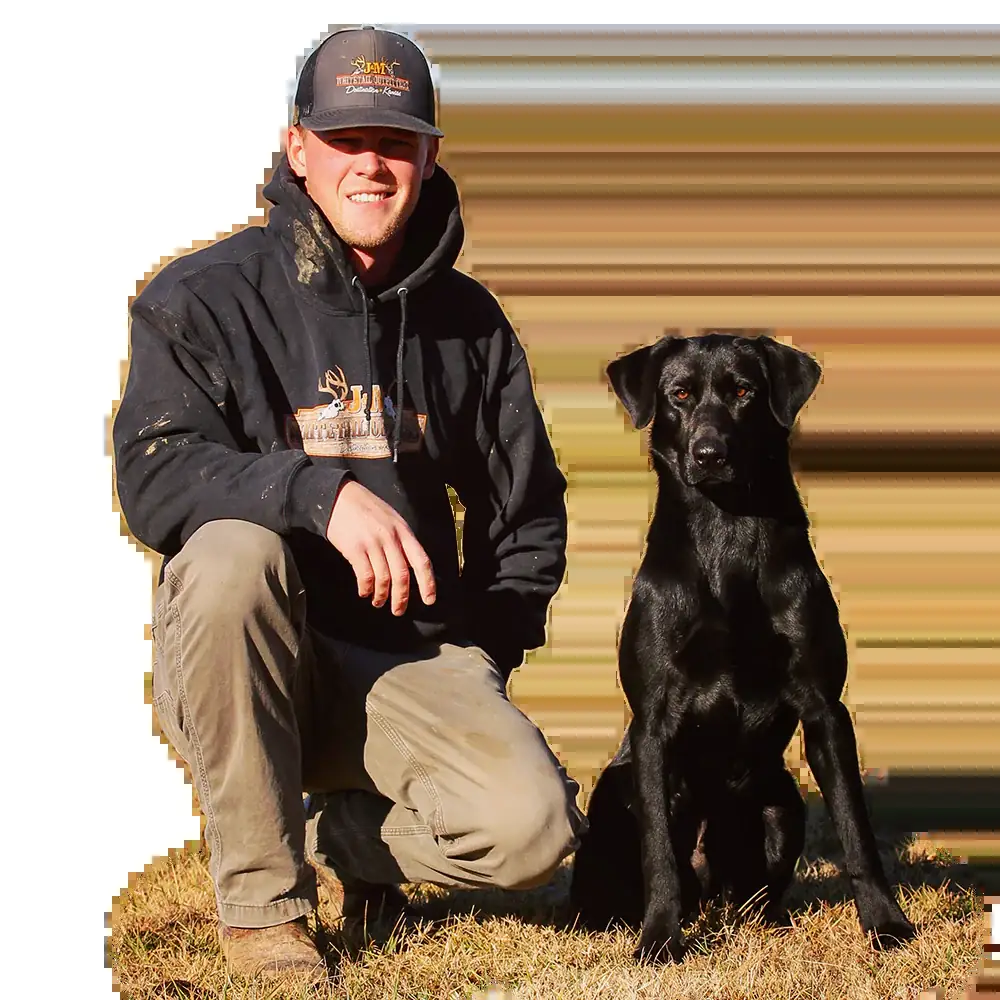 Brian kneeling in the field with his black lab