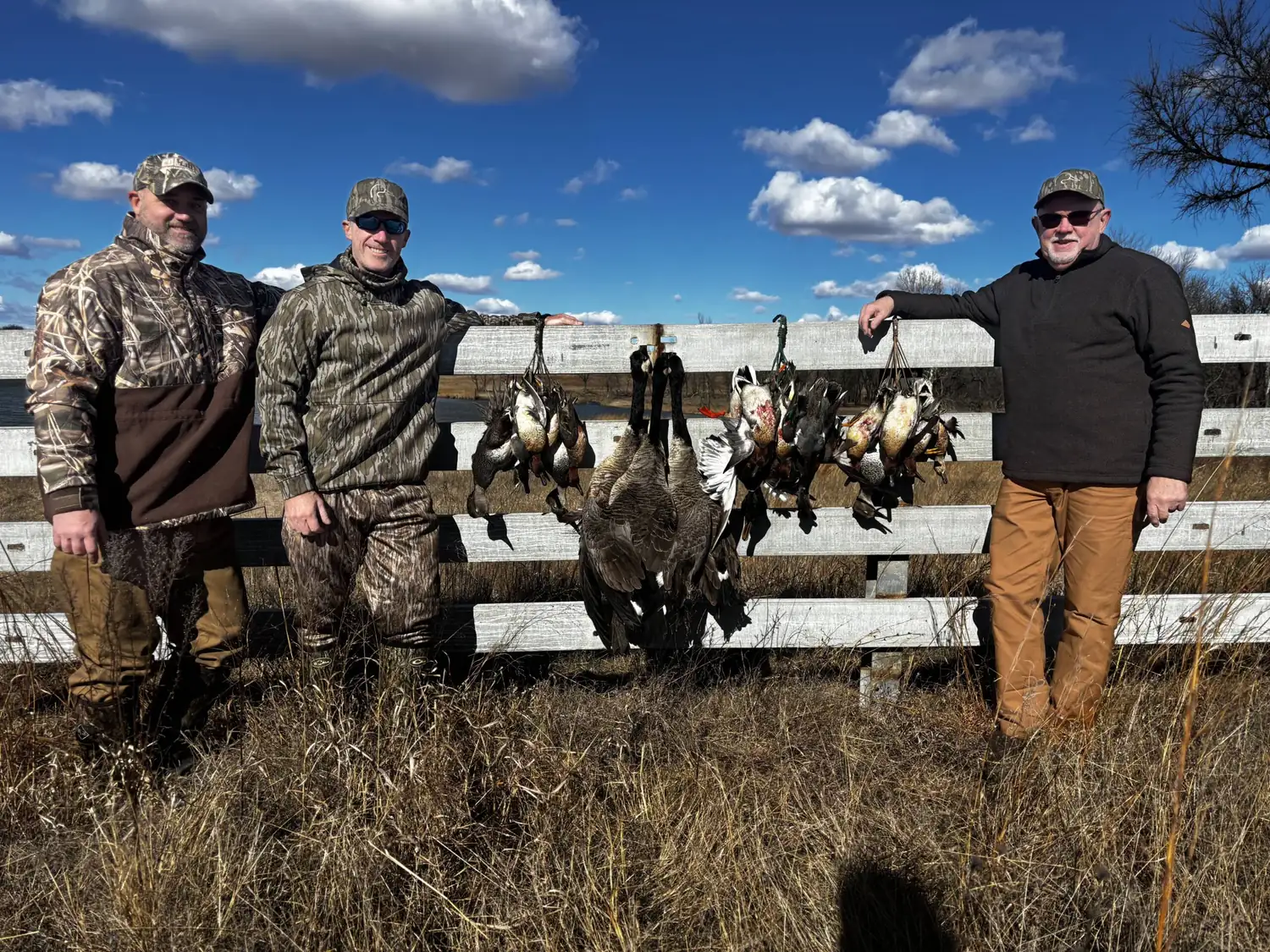 Three hunters with a morning limit hung along the fence rail