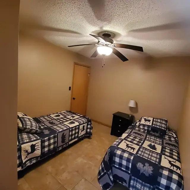 Twin bedroom with ceiling fan at Lake Lodge
